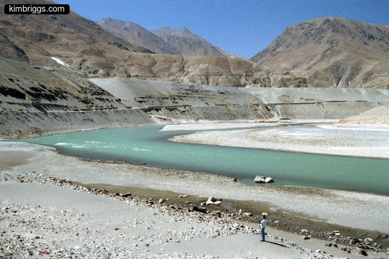 Aqua river in Tibet mountains with man for scale.