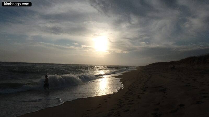 Silhouette of man on beach at sunset.