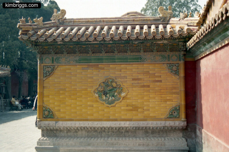 Wall with yellow ceramic tiles and green trim.