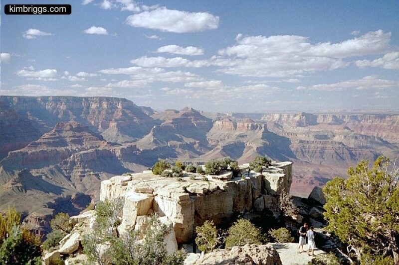 People at large white rock in front of Grand Canyon.