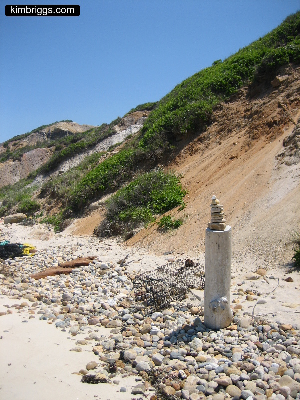 Smooth stones on beach near sandy hill.