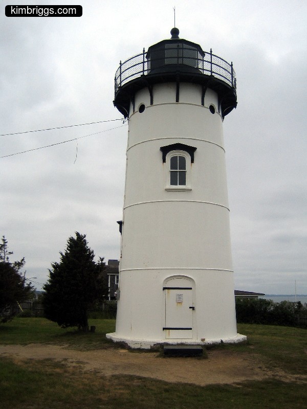 Small white lighthouse on grass.