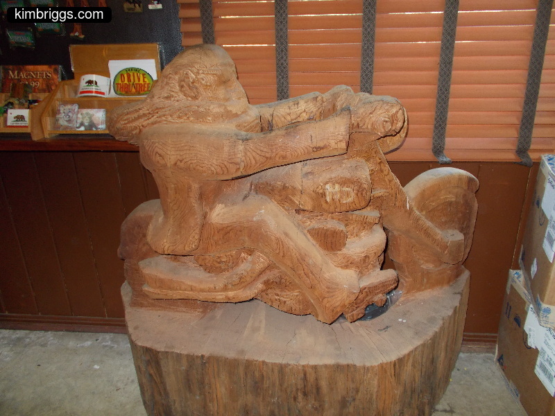 Wood carving of man on motorcycle.