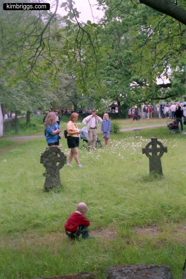 Children playing in grass near gravestones.