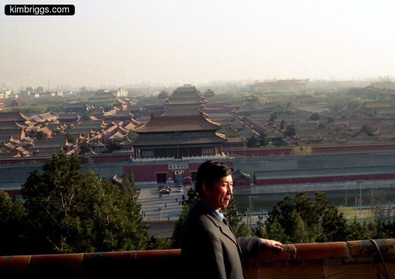 Man posing on hill above Forbidden City Beijing.