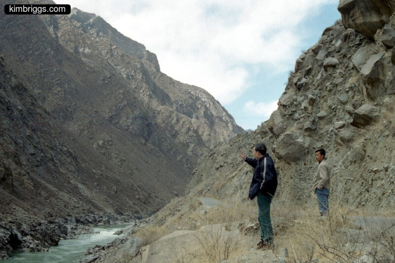 Men standing near river and rocky mountains in TIbet.
