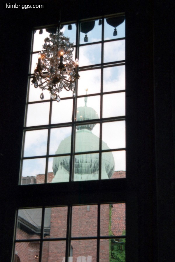 Large chandelier in front of many-paned windows.