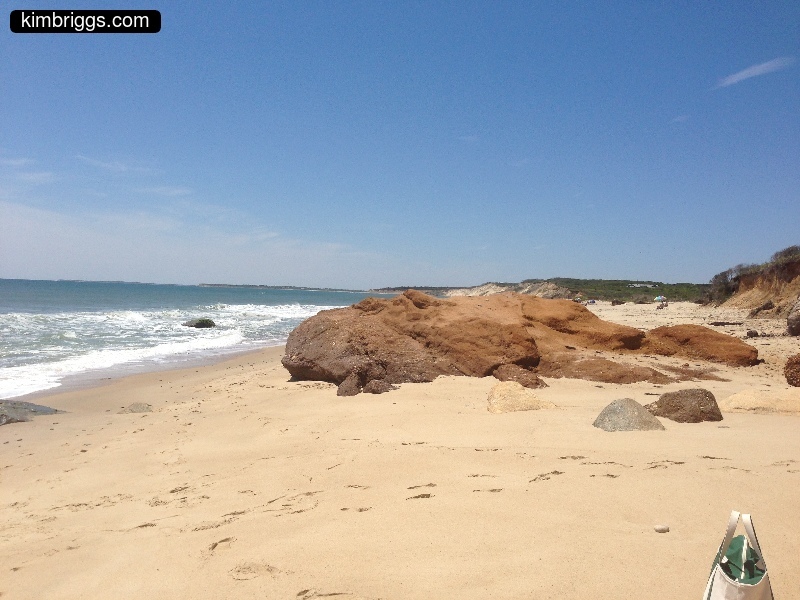 Large brown rock on sandy beach.
