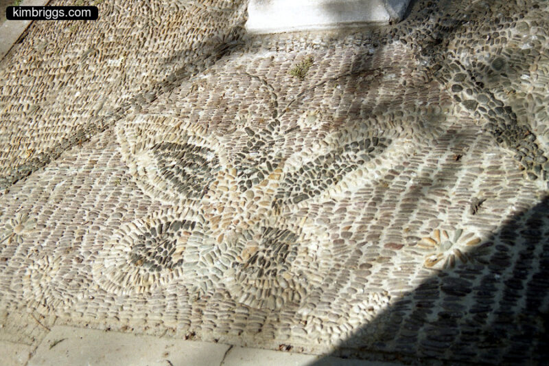 Butterfly artwork made from tiny stones in the pavement.