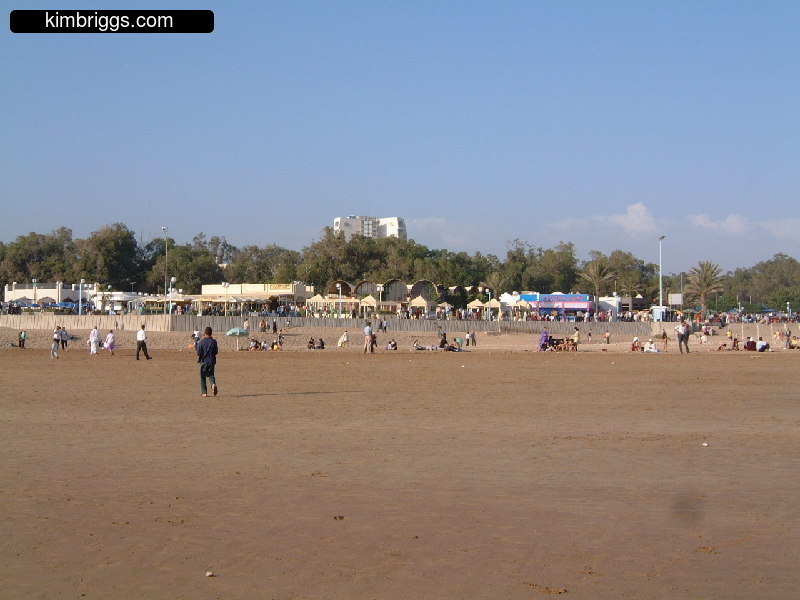 People and tents on clear sandy beach.