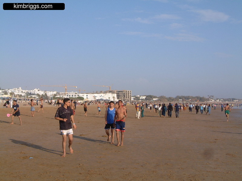People on Agadir beach with resort in background.