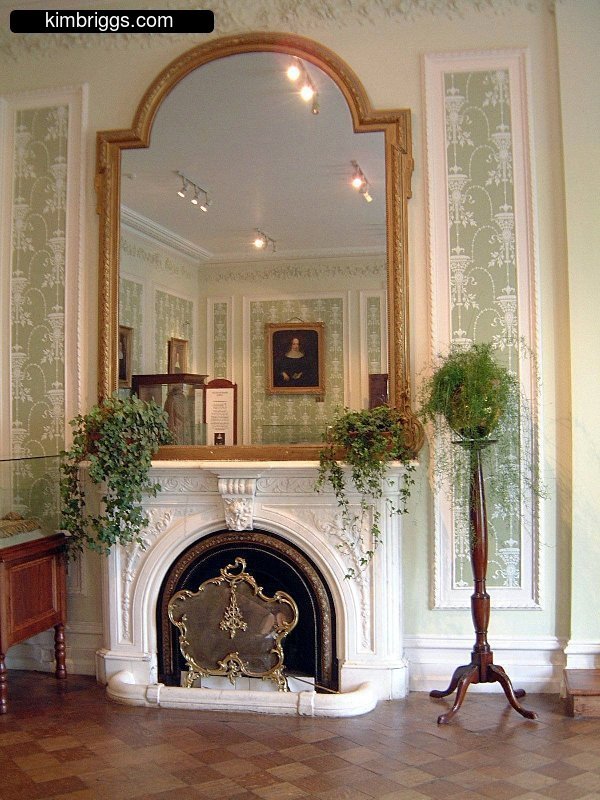 Fancy white fireplace with large mirror.