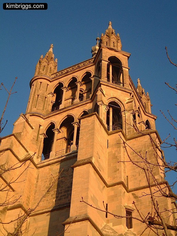Church tower colored by sunset against blue sky.