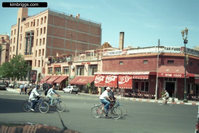 People on bikes in front of outdoor cafe.