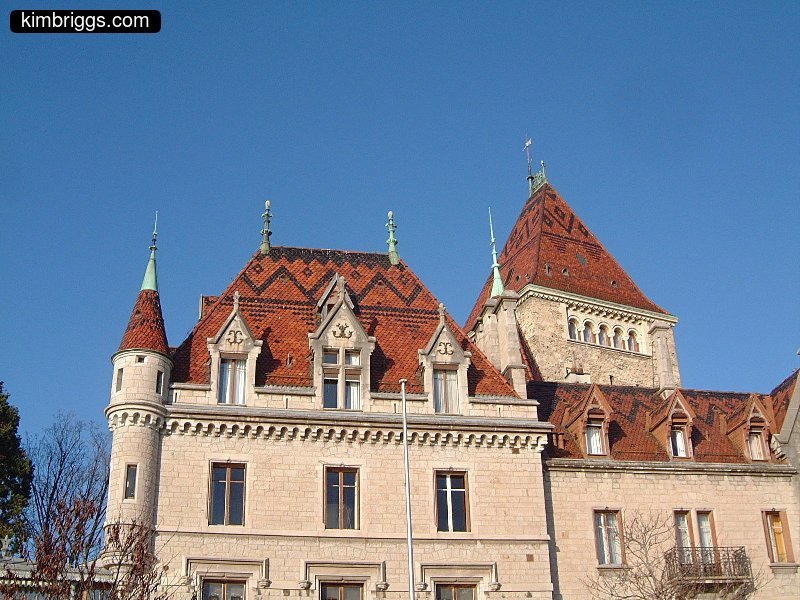 Large white stone building with red tile roof.