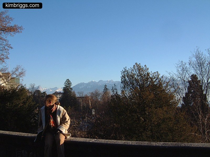 Woman on wall with mountains in background.