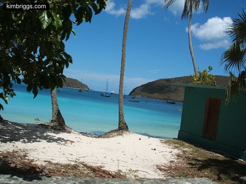 Small sandy beach with clear blue water in small bay.