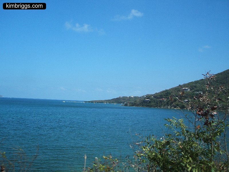 Ocean view with green hill on shore.