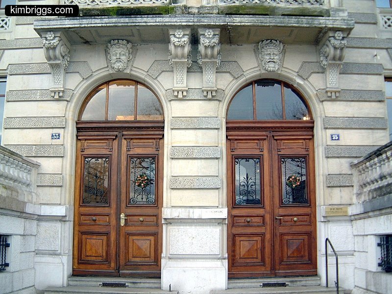 White stone building with two wooden arched doors.