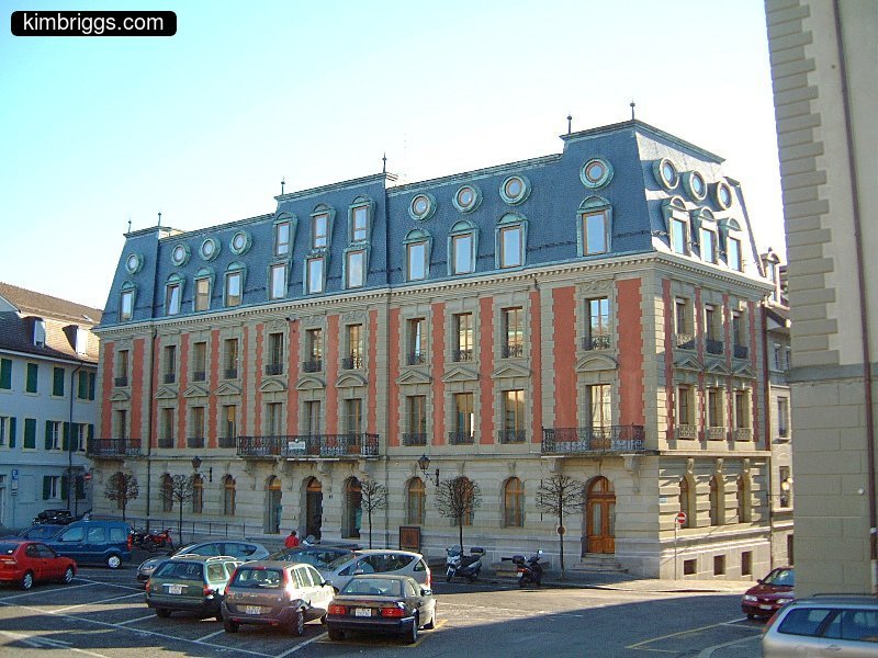 European building with white and red stones, black roof.