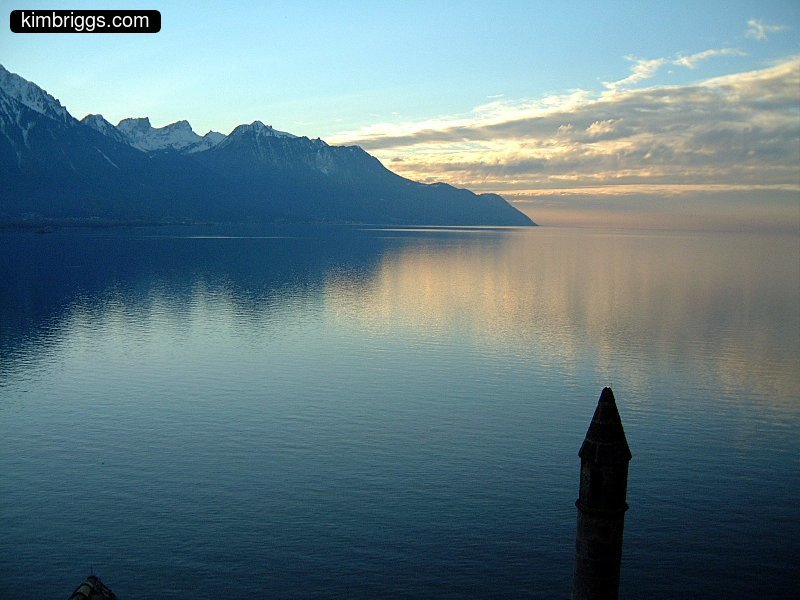 Lake with mountains and clouds mirror reflection.