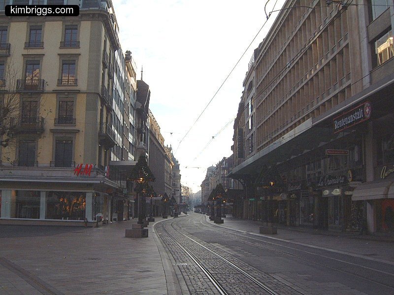 City street with overhead electric train tracks.